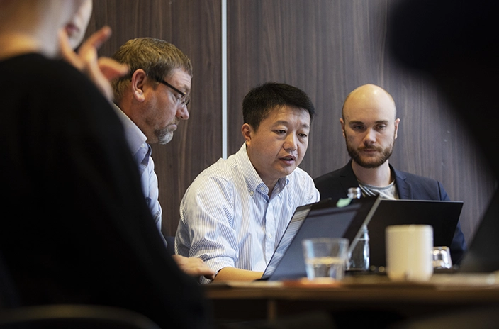A group of professionals working together on a laptop during a business meeting.