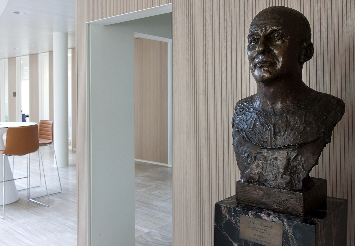 Bronze bust of J.C. Hempel displayed inside the Hempel headquarters next to a modern seating area.