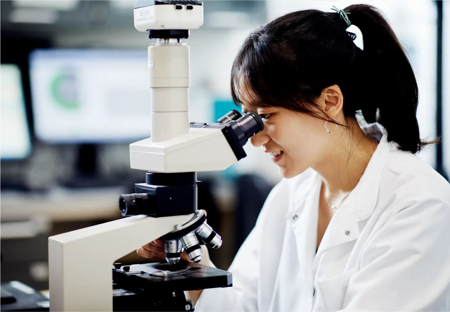 Young woman looking into microscope