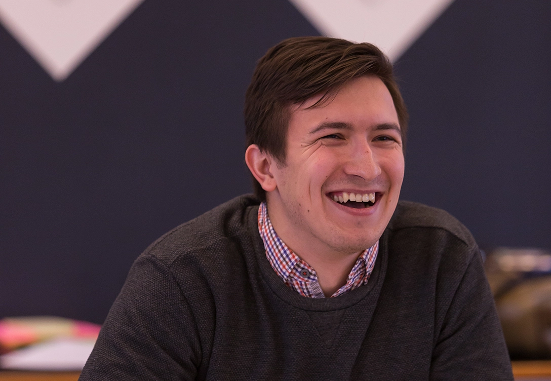A young man Rifnur Latipov smiling warmly while participating in a casual discussion.