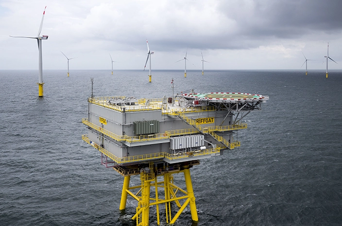 An offshore wind substation platform and wind turbines at the wind farm in China sea.